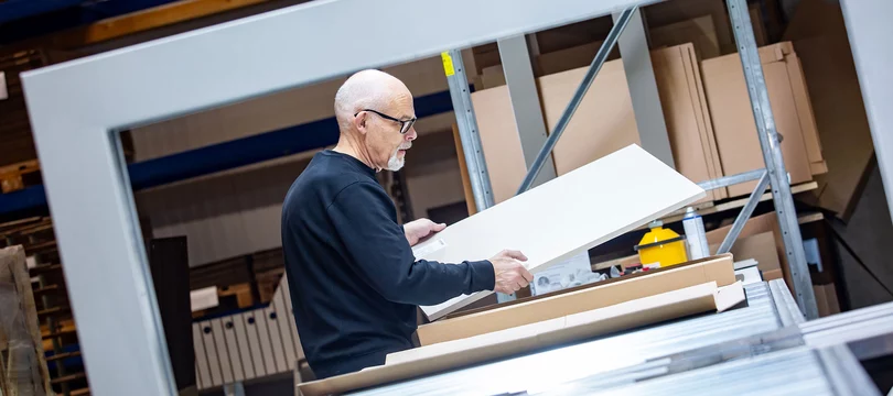 Mitarbeiter prüft sorgfältig ein Möbelteil in der Produktion – ein Beispiel für die gelebten Visionen und Werte